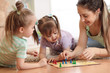 © Oksana Kuzmina - Happy family. Young mother playing ludo boardgame with her children daughters while spending time together at home.