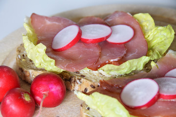 sandwich with smoked ham on a lettuce leaf with slices of radish