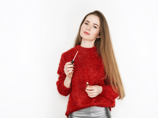 Wall Mural - Spectacular blonde woman in red blouse silver leather pants posing with lip glow balm in front of white wall. Graceful girl gorgeous long hair having fun on photoshoot.