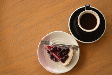 Wall Mural - cup of americano coffee and blueberry cheese pie on table in cafe