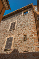 Stone wall with closed windows and gargoyle in niche, at the gorgeous medieval hamlet of Les Arcs-sur-Argens, near Draguignan. Located in the Provence region, Var department, southeastern France