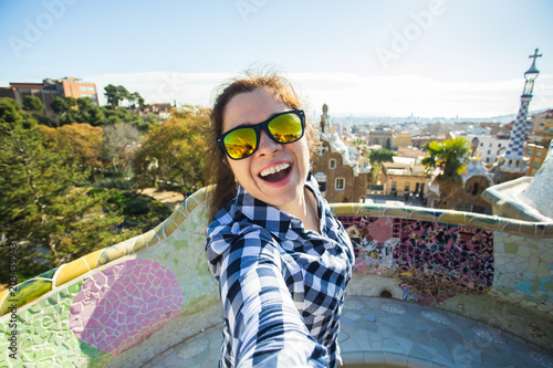 Fotografie, Tablou Young happy woman making selfie portrait with smartphone in Park Guell, Barcelona, Spain