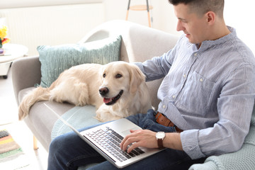 Portrait of owner with his friendly dog using laptop at home