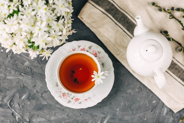 tea Cup, teapot, book, white flowers on dark background, flatlay