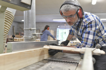 Canvas Print - Wood worker cutting piece of wood with machine