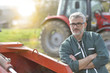 © goodluz - Farmer standing by tractor outside the barn