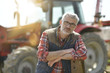 © goodluz - Farmer standing by tractor outside the barn