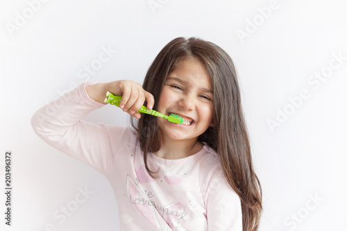 Fotografía Little cute child girl brushing her teeth on white background