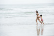 © nareekarn - Mother and daughter walking on the beach.