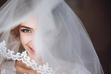 happy stylish bride smiling and looking under veil. space for text. gorgeous emotional bride getting