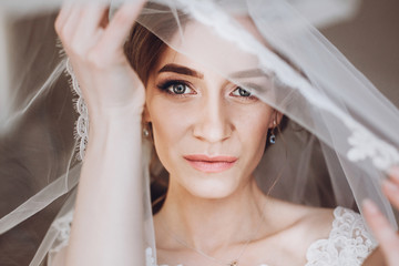 happy stylish bride looking under veil. space for text. gorgeous bride getting ready and posing in the morning. marriage concept