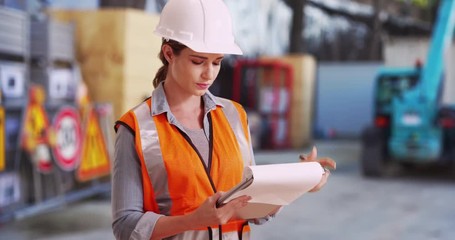 Wall Mural - Young white lady on construction site checking things off on clipboard