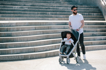 Father walking with a stroller and a baby in the city streets