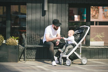 Father Walking With A Stroller And A Baby In The City Streets
