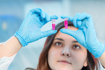 Wall Mural - Female medical worker compares test tubes with biological samples