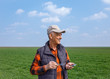 © Zoran Zeremski - Senior farmer standing in young wheat field holding phone in his hand and examining crop.
