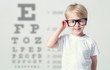 © A Stock Studio - Little boy in glasses having eye test, over eye chart. Tables vision testing. Visiting a doctor pediatric ophthalmologist.