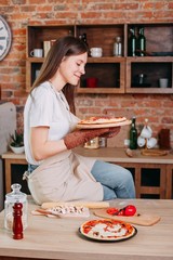 Wall Mural - Young woman baking delicious pizza to her family and friends. Cooking with love, homemade recipe, culinary, food preparing concept