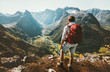 Hiking alone in Norway mountains Man with red backpack enjoying landscape on cliff solo traveling healthy lifestyle concept active summer vacations