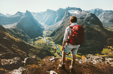 hiking alone in norway mountains man with red backpack enjoying landscape on cliff solo traveling he