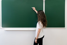 A Teenage Girl Stands By The School Board With Chalk In Her Hand And Writes. The Beginning Of The School Year. Place For The Inscription. Copy Space. Mockup