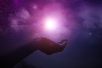 Hands holding light with night sky and stars in the background