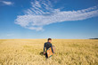 © 072Y - Surfer waits for a wave. Abstraction art. The field of rye. A guy with a surfboard and a black diving suit. Blue sunny sky with clouds