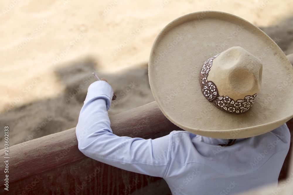 sombrero cigarette A mexican charro with his sombrero smoking a cigarette while watching  another charros Stock Photo