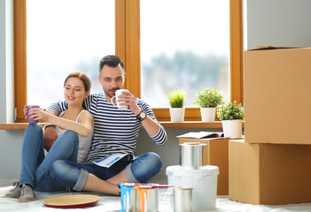 Wall Mural - Portrait happy smiling young couple painting interior wall of new house. Young couple