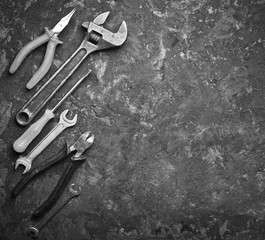 Wall Mural - Copy space of working tools on a black concrete surface. Nippers, wrench keys, pliers, screwdriver. Top view.