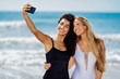 © javiindy - Two women taking selfie photograph with smartphone in the beach