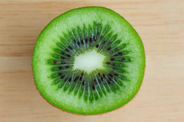 Wall Mural - Fresh and juicy kiwi fruit with cross section cut in close up view macro concept on wood table for background or wallpaper. Kiwi have sweet and sour taste and have high vitamin c and antioxidant.