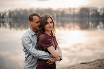 Man hugging from behind woman on the background of lake