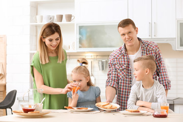 Wall Mural - Parents and cute little children having breakfast with tasty toasted bread at table in kitchen