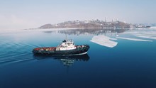 A Towboat Goes Among The Ice On The Background Of The City