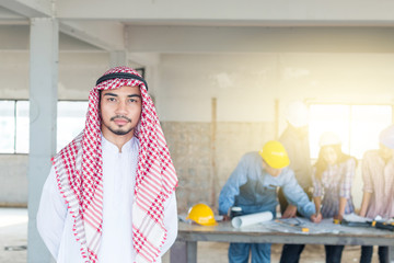 Wall Mural - Arab engineer with Group of engineer background, They are checking the blueprint and talking about construction project with commitment to success at construction site