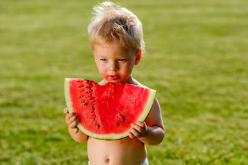 Wall Mural - One year old baby boy eating watermelon in the garden