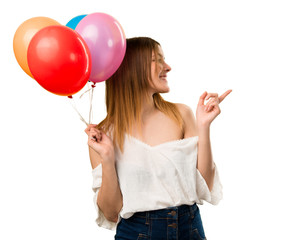 Wall Mural - Beautiful young girl holding a balloon and pointing to the lateral