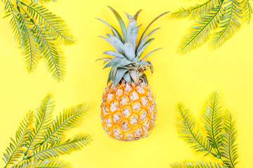  Summer holiday background. Tropical plant leaves and pineapple on yellow background. Flat lay