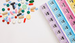 Assorted pharmaceutical medicine pills, tablets and capsules over white background with daily pill organizer