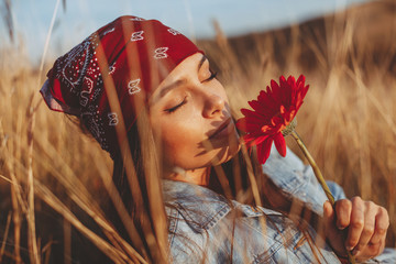 Beautiful young woman holding flower in a meadow