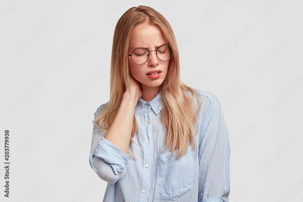 Tired female office worker in spectacles has pain in neck as sat long ...