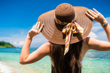 Woman In Summer Vacation Wearing Straw Hat And Beach Dress Enjoying The View At The Ocean
