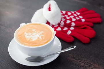 Coffee cup with knitted gloves.