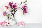 Fototapeta Desenie - still life with bouquet of pink magnolia flowers in bottles with gift box and macaroons on white table