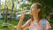 © alexeg84 - Young woman stand on countryside path in asian village and drinking water.