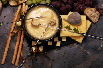 Gourmet Swiss fondue dinner on a winter evening with assorted cheeses on a board alongside a heated pot of cheese fondue