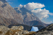 © Travel Wild - A single blue tent seen against Dhaulahaar peaks of Himalayas in Triund. Sunny day whit some clouds. Dharamshala, Himachal Pradesh. India