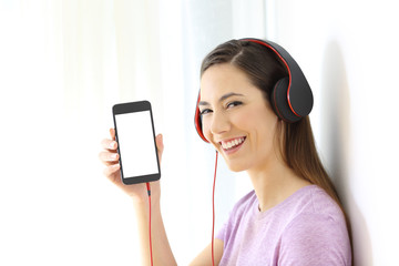 Wall Mural - Girl listening to music and showing phone screen