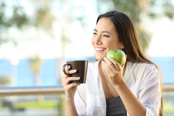 Wall Mural - Happy woman holding an apple and a coffee mug